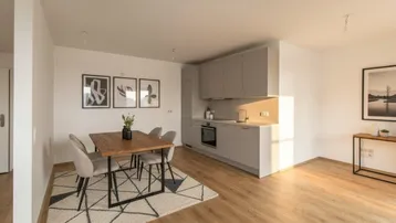 Moderne offene Küche mit grauen Schränken und Essbereich mit Holztisch.