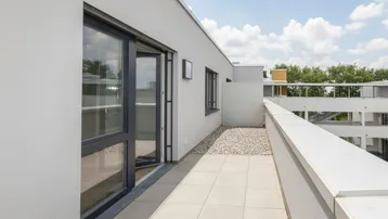 Helle Dachterrasse mit Fliesenboden und Kiesstreifen, ideal zum Entspannen im Freien.