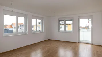 Helles und geräumiges Zimmer mit Laminatboden und direktem Zugang zum Balkon.