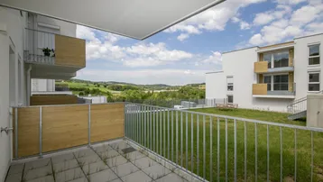 Geräumige Terrasse mit Fliesenboden und weitem Blick ins Grüne und auf die umliegende Landschaft.