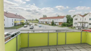Geräumiger Balkon mit grüner Brüstung und Blick auf die umliegende Wohnsiedlung.