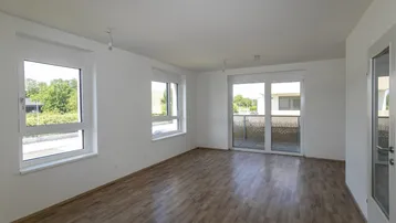 Helles Wohnzimmer mit Laminatboden, großen Fenstern und Zugang zu einem Balkon.