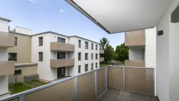 Balkon mit Fliesenboden und Blick auf die umliegenden modernen Wohngebäude.