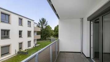 Balkon mit Blick auf die grüne Umgebung und angrenzende Wohngebäude, ideal zum Entspannen.