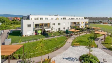 Moderne Wohnanlage mit hellen Fassaden, Balkonen und gepflegten Grünflächen inklusive Spielplatz.