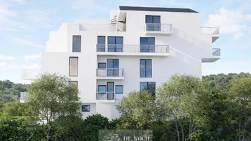 Moderne weiße Wohnanlage mit gestuften Balkonen und umgebender Natur.