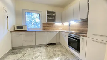 Moderne Küche mit hellen Schränken, Holzoptik-Arbeitsplatte und Fliesenboden.