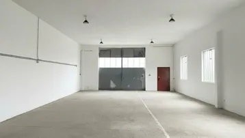 Geräumige, leere Lagerhalle mit Betonboden, hohen Decken und großen Toren für den Zugang.