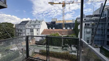 Blick vom Balkon auf die umliegenden Gebäude und Dächer mit einem Baukran im Hintergrund.