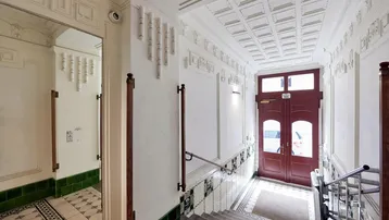 Eleganter Eingangsbereich mit hohen Decken, verzierten Wänden und gemusterten Bodenfliesen, der den Charme eines Altbaus widerspiegelt.