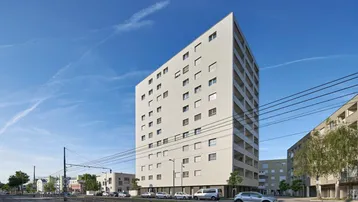 Modernes Wohngebäude mit heller Fassade und vielen Fenstern unter blauem Himmel.