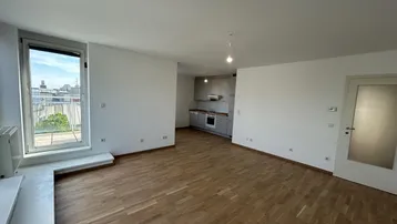 Heller Wohnbereich mit Parkettboden und integrierter Küche, ideal für offenes Wohnen.
