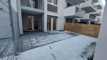 Terrasse mit angrenzendem Gartenbereich, teilweise mit Schnee bedeckt, und Zugang zu Innenräumen.