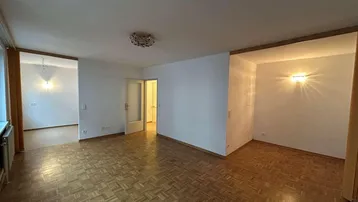 Geräumiges Wohnzimmer mit Fischgrätparkettboden und einem Kronleuchter, bereit zur individuellen Gestaltung.