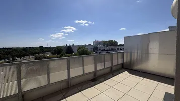 Geräumige Dachterrasse mit Fliesenboden und weitem Blick über die Stadt und grüne Umgebung.