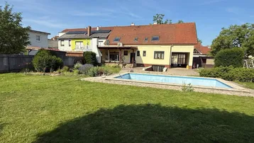 Großer Garten mit Rasenfläche und einem leeren Swimmingpool hinter dem Haus.