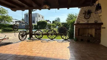 Überdachte Terrasse mit rustikalem Außenkamin und traditioneller Dekoration, ideal für gesellige Abende.