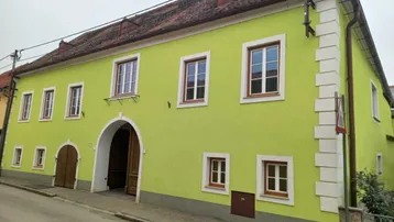 Auffällige grüne Fassade eines historischen Gebäudes mit traditionellen Fenstern und Torbogen.
