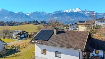 Haus mit Solaranlage auf dem Dach und beeindruckendem Bergpanorama im Hintergrund.