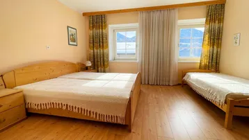 Gemütliches Schlafzimmer mit zwei Holzbetten, Parkettboden und malerischem Bergblick aus den Fenstern.