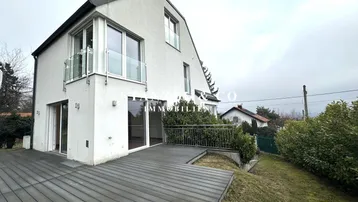 Moderne Architektur des Hauses mit großer Holzterrasse und Blick auf die Umgebung.