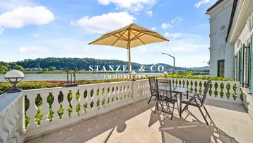 Terrasse mit Balustrade, Sitzgelegenheiten und weitem Blick auf den Fluss und die Landschaft.