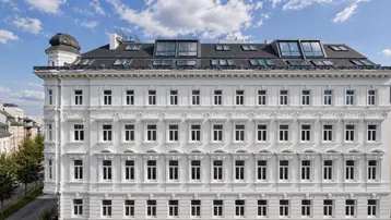 Elegante weiße Fassade eines historischen Gebäudes mit modernen Dachfenstern und vielen Details.