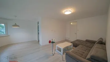 Helles Wohnzimmer mit modernem Laminatboden und einer gemütlichen Sitzecke.