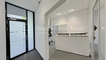 Moderner Empfangsbereich eines Büros mit Glastür, Rezeptionstresen und Teppichboden.