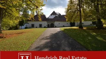 Eindrucksvolles historisches Anwesen mit langer Zufahrt, umgeben von altem Baumbestand und grünen Wiesen.