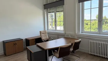 Geräumiges Büro mit hellem Laminatboden, großen Fenstern und Blick ins Grüne, ausgestattet mit modernen Büromöbeln.