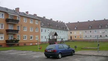 Mehrere Wohngebäude mit farbigen Fassaden, einem gemeinsamen Garten und einem Spielplatz.