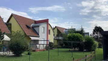 Mehrere Reihenhäuser mit Gärten und roten Ziegeldächern unter bewölktem Himmel.
