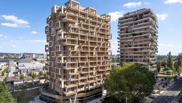 Moderne Hochhäuser mit vielen Balkonen und einer markanten Architektur unter blauem Himmel.