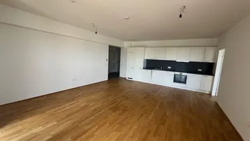 Offener Wohnbereich mit Holzboden und einer modernen, weißen Küchenzeile.