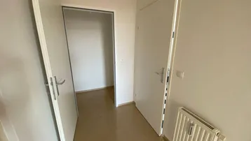 Heller Flur mit mehreren weißen Türen und einem Heizkörper, der zu verschiedenen Räumen führt.