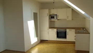 Helle Einbauküche im Dachgeschoss mit Holz-Arbeitsplatte und Parkettboden.