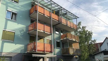 Mehrfamilienhaus mit moderner Fassade und mehreren Balkonen, teilweise überdacht.
