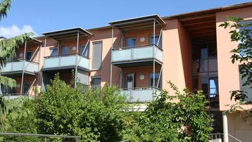 Mehrfamilienhaus mit mehreren Balkonen und moderner Architektur in sonniger Lage.