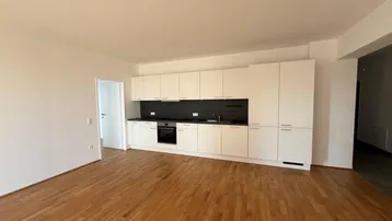 Heller Wohnbereich mit moderner weißer Einbauküche und hochwertigem Parkettboden.