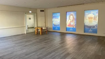 Großer, heller Mehrzweckraum mit modernem Laminatboden und Einbaustrahlern in der Decke.