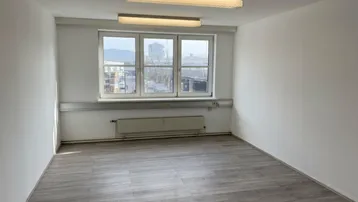 Leerer Büroraum mit großen Fenstern, Heizkörper und Deckenbeleuchtung, bereit zur individuellen Gestaltung.