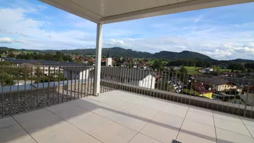 Geräumige Dachterrasse mit moderner Überdachung und weitem Blick über die Landschaft und Berge.