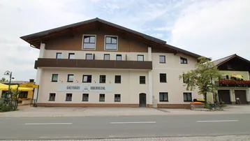Mehrstöckiges Gebäude mit traditioneller Architektur, Balkonen und einem Gasthaus im Erdgeschoss.