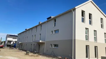 Neubau-Reihenhäuser in moderner Architektur mit heller Fassade und Baustellenbereich.