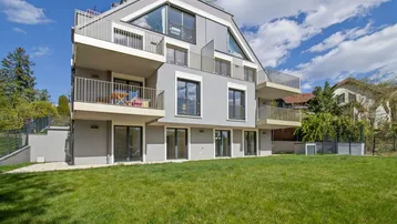 Modernes Apartmentgebäude mit mehreren Balkonen und einer gepflegten Rasenfläche im Vordergrund.