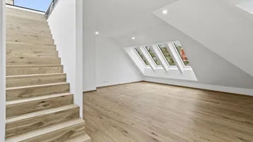 Helles Dachgeschosszimmer mit Holztreppe und großen Dachfenstern, das viel Tageslicht bietet.