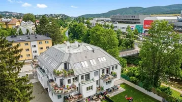 Luftaufnahme des Wohngebäudes mit Balkonen, Garten und Blick auf die umliegende Bebauung.