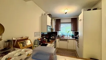 Funktionale Küche mit weißen Schränken, Holz-Arbeitsplatten und einem Fenster für natürliches Licht.