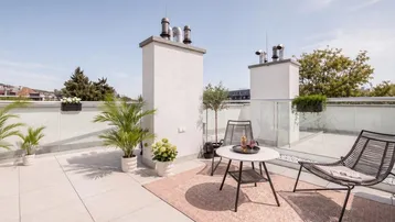 Geräumige Dachterrasse mit modernen Gartenmöbeln, Pflanzen und weitem Blick über die Umgebung.